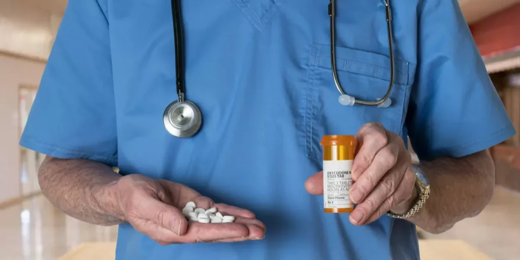 Doctor holding opioid pills and prescription bottle, highlighting safer alternatives for pain management