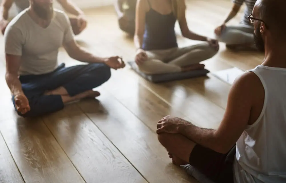 A group of people sitting peacefully in a indoor yoga room, engaging in a wellness activity that promotes mental health and supports their recovery journey from addiction. This tranquil scene emphasizes the importance of healthy habits and the treatment process in achieving long-term sobriety.