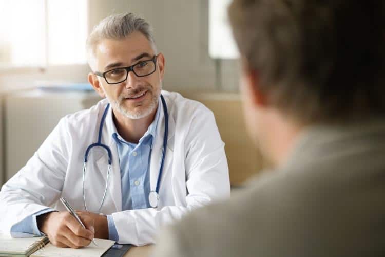 Consult a Medical Professional Smiling doctor looks at patient who wants to quit drinking