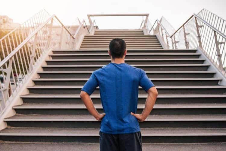 recovery process Determined athletic man stands at the bottom of a steep staircase